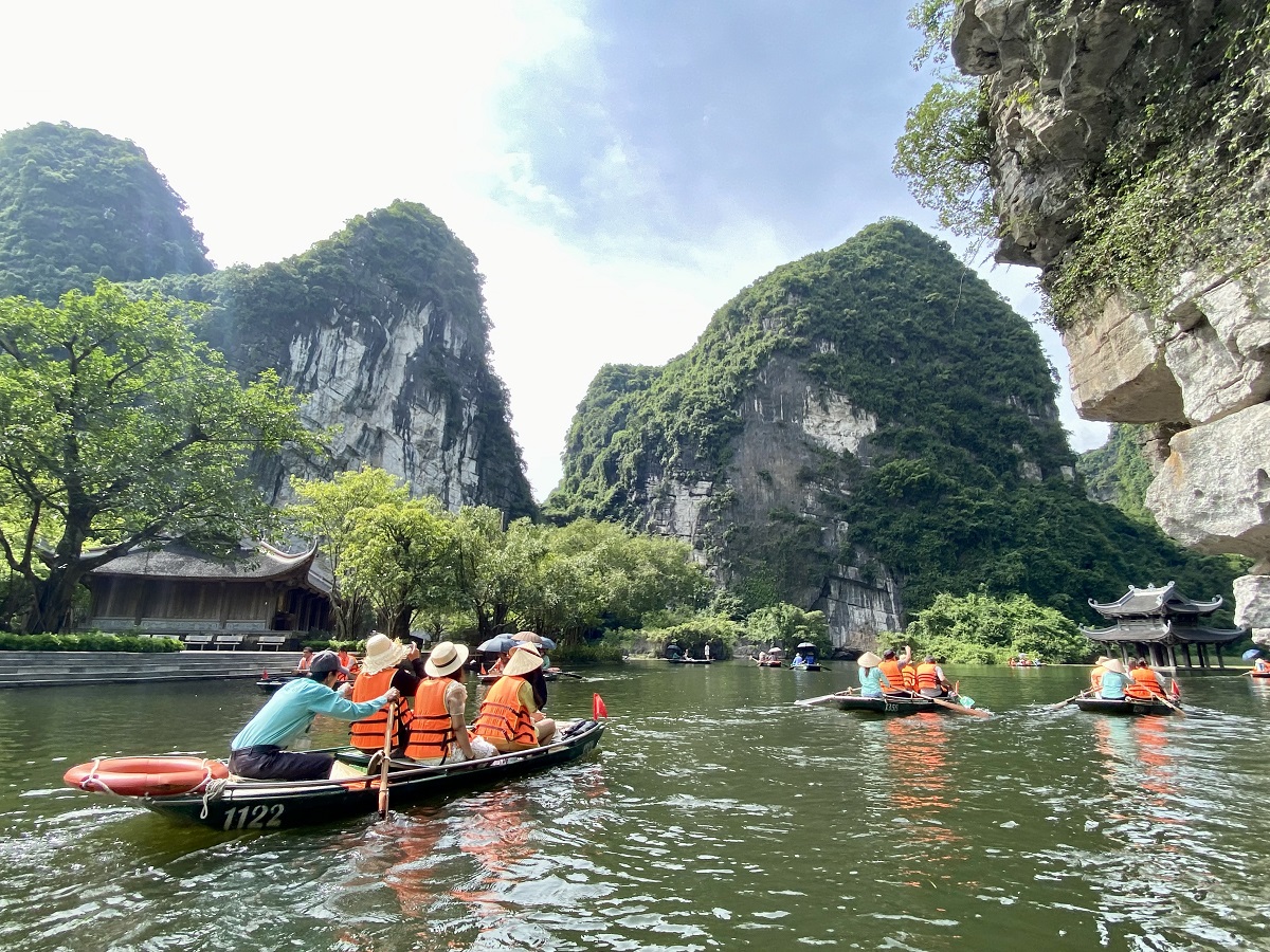 Đoàn khách tham quan đang ngắm nhìn những vách đá vôi đáng kinh ngạc ở Tràng An